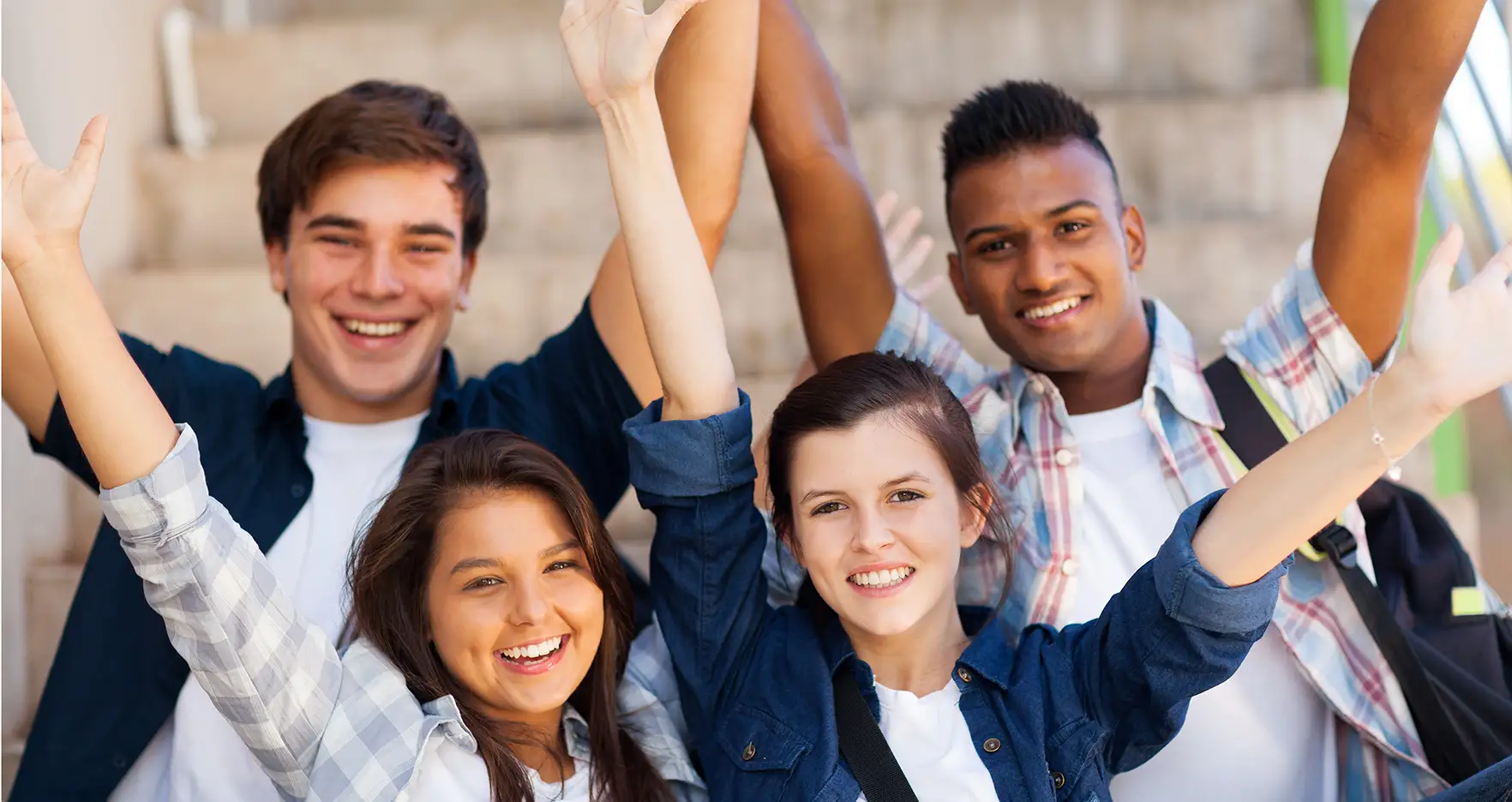 Image of a group of teenager with their hands up in the air.